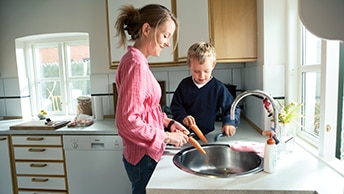 nainen laittaa ruokaa poikansa kanssa